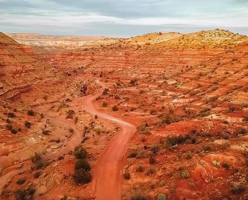 A dirt road leads through the center of a red-striped canyon in the Vermilion Cliffs on the Utah/Arizona border.